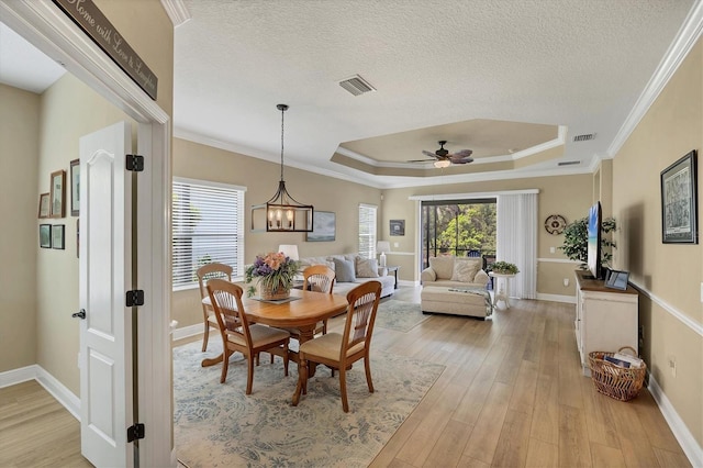 2628 Sapphire Blue Ln, Bradenton, FL 34211 - dining room featuring light wood finished floors, a raised ceiling, baseboards, a ceiling fan, and ornamental molding