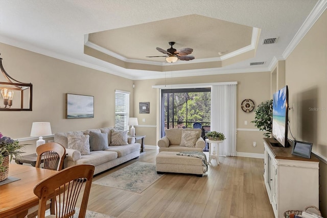 2628 Sapphire Blue Ln, Bradenton, FL 34211 - living room featuring a raised ceiling, a ceiling fan, light wood-style floors, crown molding, and baseboards