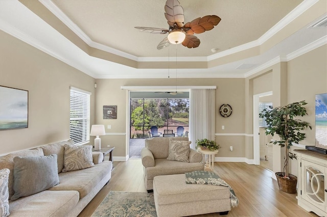 2628 Sapphire Blue Ln, Bradenton, FL 34211 - living area featuring a tray ceiling, light wood-style flooring, ceiling fan, crown molding, and baseboards