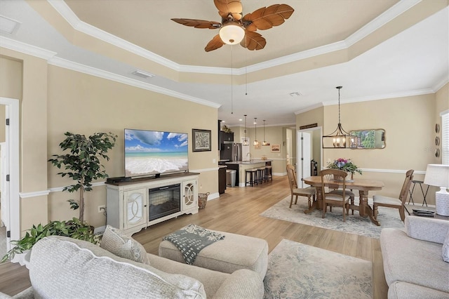 2628 Sapphire Blue Ln, Bradenton, FL 34211 - living room with a tray ceiling, light wood-style flooring, a ceiling fan, baseboards, and ornamental molding