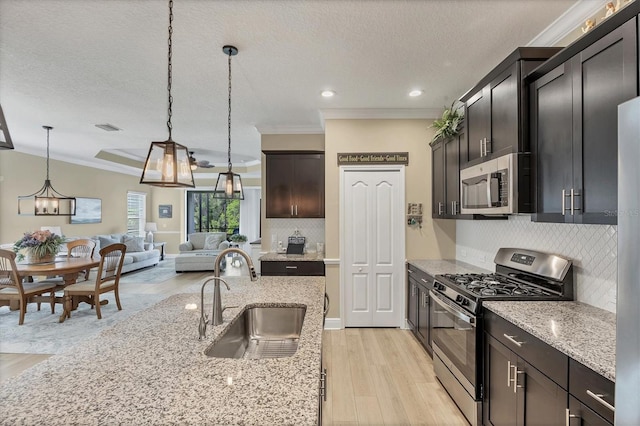 2628 Sapphire Blue Ln, Bradenton, FL 34211 - kitchen with stainless steel appliances, a sink, crown molding, a chandelier, and light wood-style flooring
