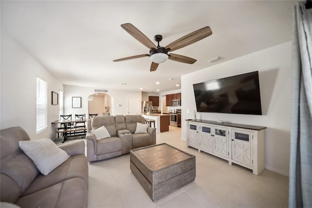living room featuring light tile patterned flooring, visible vents, recessed lighting, a ceiling fan, and arched walkways