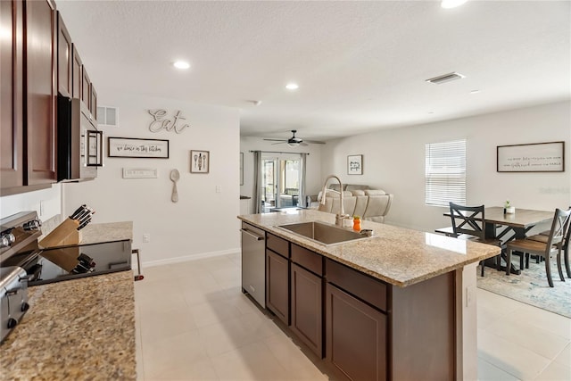 kitchen with visible vents, a kitchen island with sink, stainless steel appliances, a ceiling fan, and a sink