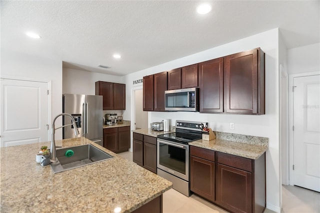 kitchen featuring recessed lighting, stainless steel appliances, a sink, visible vents, and dark brown cabinetry