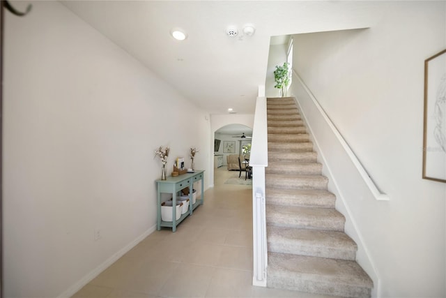 stairway with baseboards, arched walkways, and recessed lighting