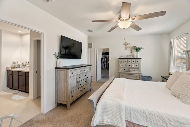 bedroom with light carpet, a closet, connected bathroom, and a spacious closet