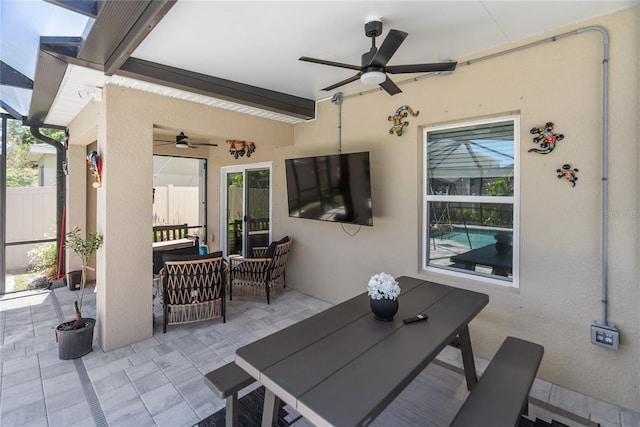 view of patio featuring fence, a lanai, an outdoor living space, and ceiling fan