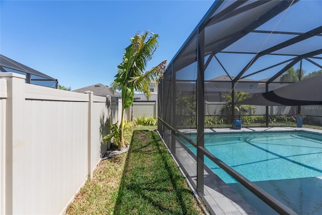 view of swimming pool featuring glass enclosure, fence, and a fenced in pool