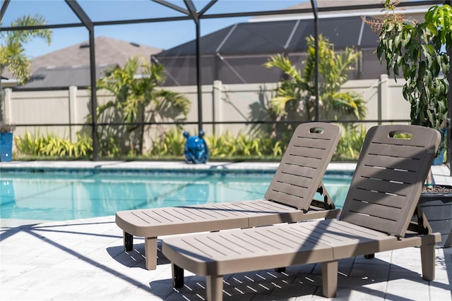 pool featuring glass enclosure and a patio area