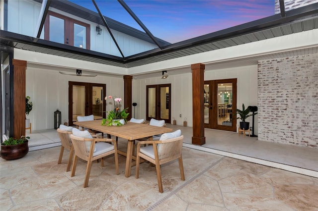 1208 Oak Hammock Rd, Sarasota, FL 34240 - patio terrace at dusk with french doors, outdoor dining area, and glass enclosure
