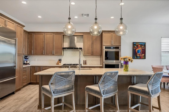 17675 Azul Dr, Lakewood Ranch, FL 34202 - kitchen featuring visible vents, wall chimney range hood, appliances with stainless steel finishes, light wood-style floors, and decorative backsplash