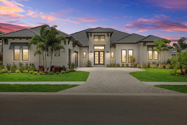 9241 Starry Night Ave, Sarasota, FL 34241 - view of front facade featuring a tiled roof, a lawn, stucco siding, driveway, and french doors