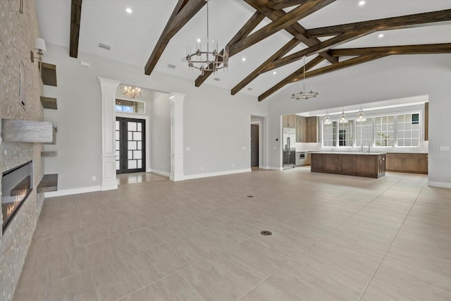 9241 Starry Night Ave, Sarasota, FL 34241 - unfurnished living room featuring decorative columns, a notable chandelier, high vaulted ceiling, beam ceiling, and a fireplace