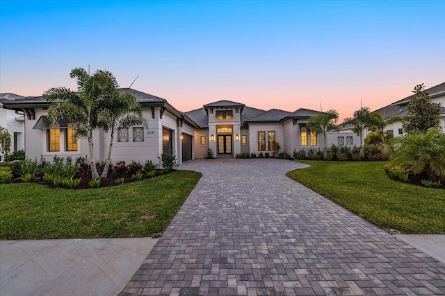 9241 Starry Night Ave, Sarasota, FL 34241 - prairie-style house featuring decorative driveway, an attached garage, a front lawn, stucco siding, and french doors