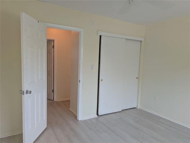 unfurnished bedroom with light wood finished floors, a closet, and baseboards