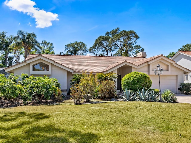 view of front of house featuring a tiled roof, stucco siding, a garage, and a front lawn