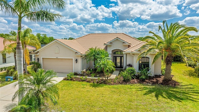 mediterranean / spanish home featuring an attached garage, concrete driveway, a tile roof, a front lawn, and stucco siding