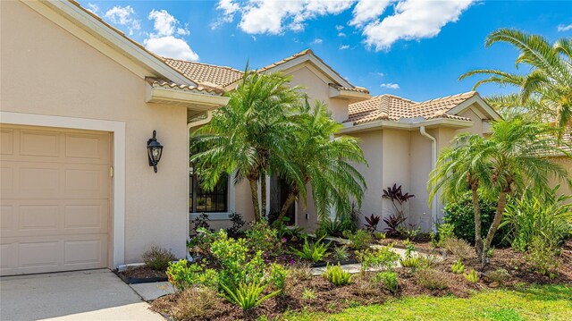 view of exterior entry with a tile roof, stucco siding, and an attached garage