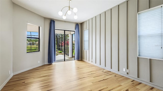 spare room with a notable chandelier and wood finished floors