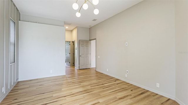 unfurnished room featuring visible vents, a notable chandelier, baseboards, and light wood-type flooring