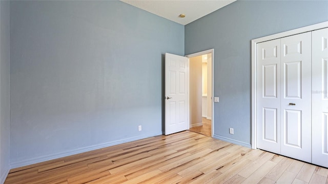 unfurnished bedroom with a closet, baseboards, and wood finished floors