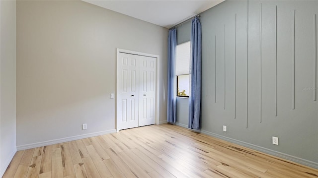 unfurnished bedroom with a closet, baseboards, and light wood-type flooring
