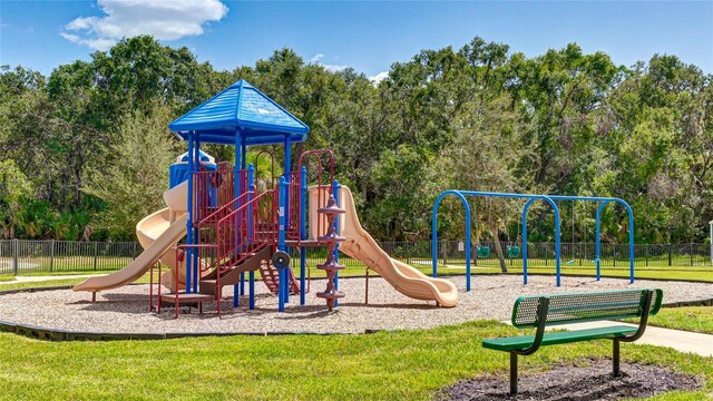 communal playground featuring a yard and fence