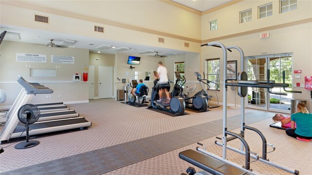 workout area with baseboards, visible vents, a towering ceiling, and a ceiling fan