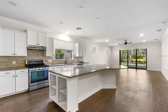 kitchen with a center island, under cabinet range hood, visible vents, stainless steel gas stove, and a sink