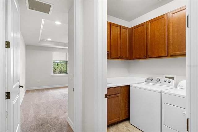 washroom featuring visible vents, baseboards, cabinet space, washing machine and dryer, and light colored carpet