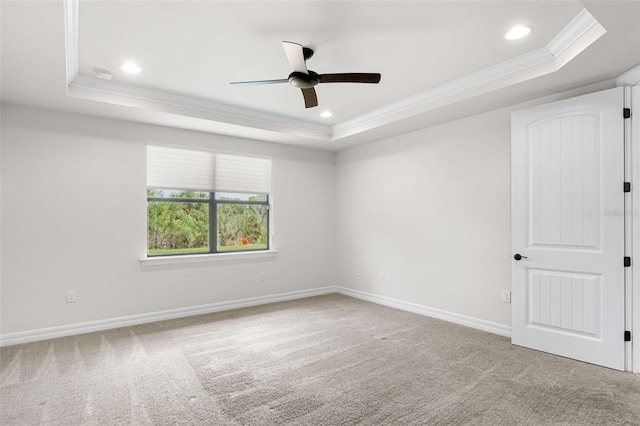 empty room featuring baseboards, a raised ceiling, crown molding, carpet floors, and ceiling fan