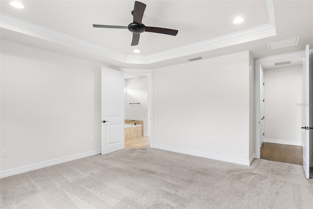 unfurnished bedroom featuring ornamental molding, a tray ceiling, and visible vents