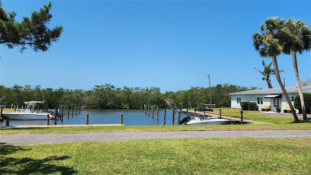 view of dock featuring a water view, boat lift, and a lawn