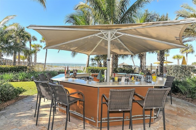 view of patio featuring exterior bar and fence