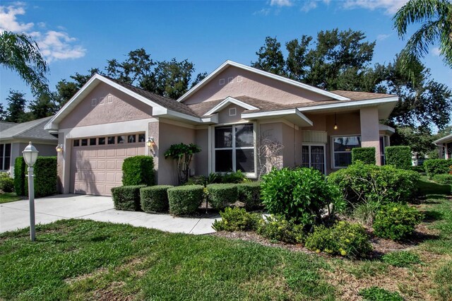 ranch-style house featuring stucco siding, a garage, concrete driveway, and a front yard