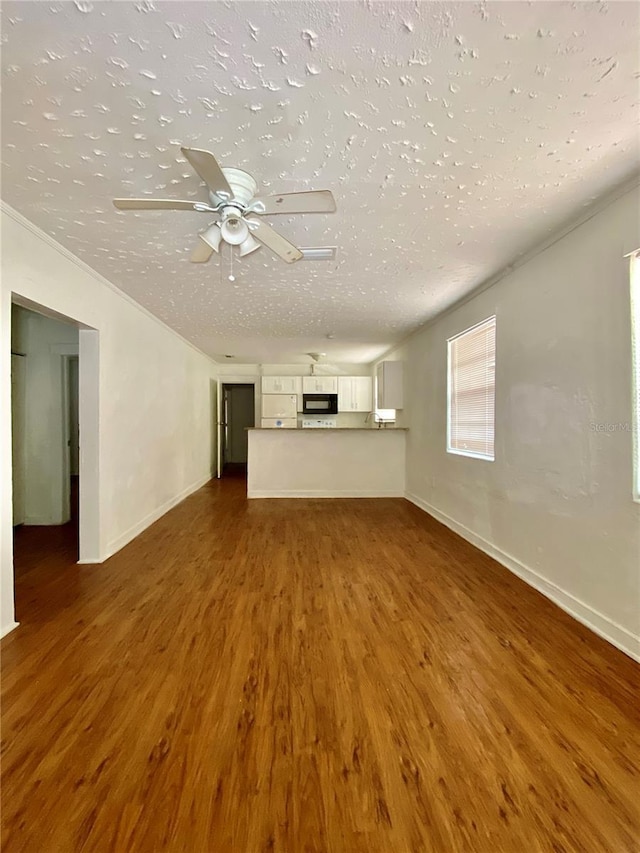 unfurnished living room featuring baseboards, a textured ceiling, a ceiling fan, a fireplace, and wood finished floors
