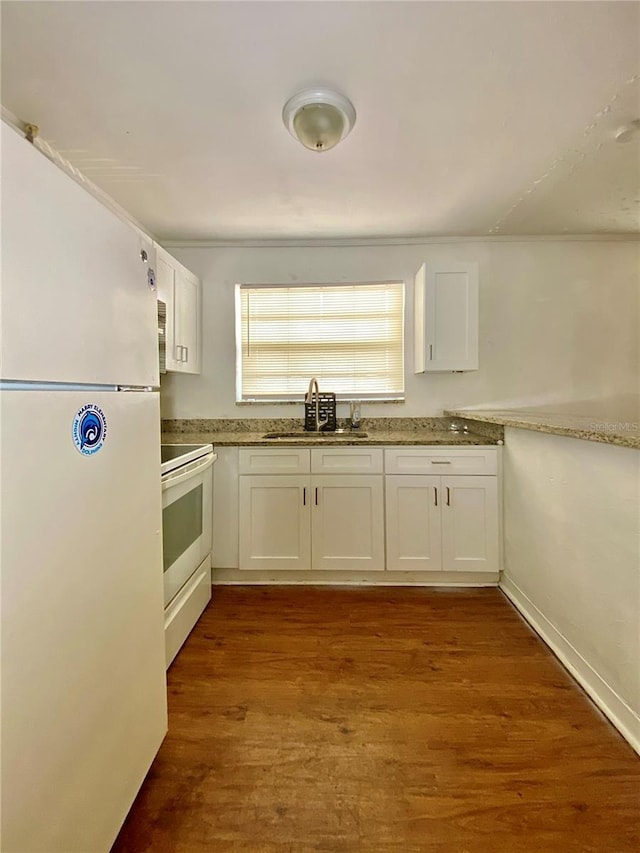 kitchen with white appliances, white cabinets, and a sink