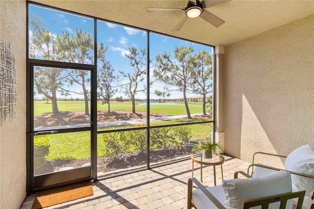 sunroom featuring a ceiling fan and golf course view