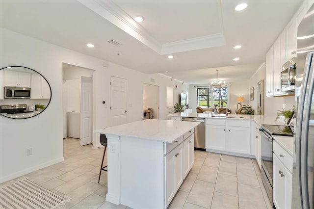 kitchen with stainless steel appliances, a peninsula, a tray ceiling, and recessed lighting