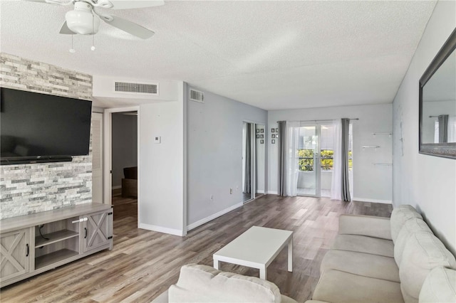 living area with a textured ceiling, visible vents, and a ceiling fan