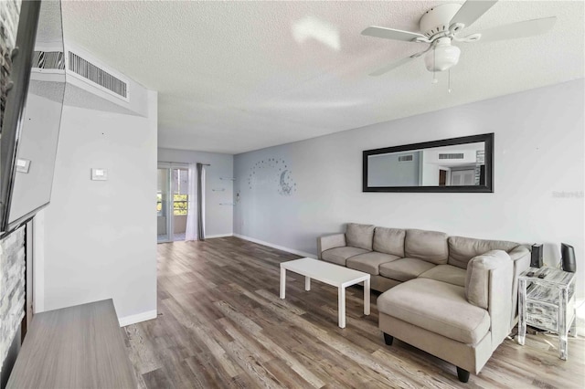 living area featuring wood finished floors, ceiling fan, and a textured ceiling