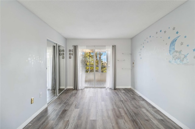 empty room featuring a textured ceiling, baseboards, and wood finished floors