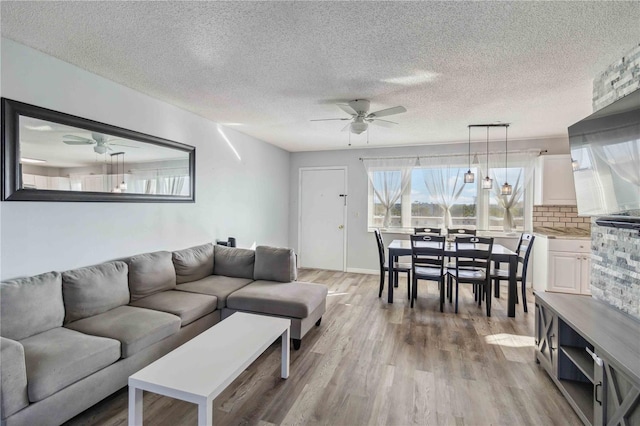 living area featuring a textured ceiling, light wood-style flooring, and a ceiling fan