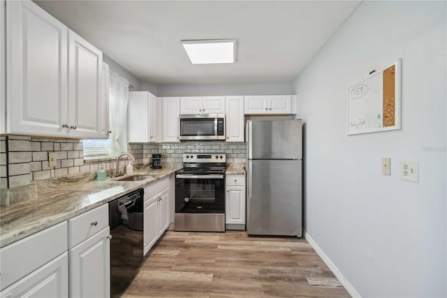 kitchen with a sink, backsplash, appliances with stainless steel finishes, and white cabinets