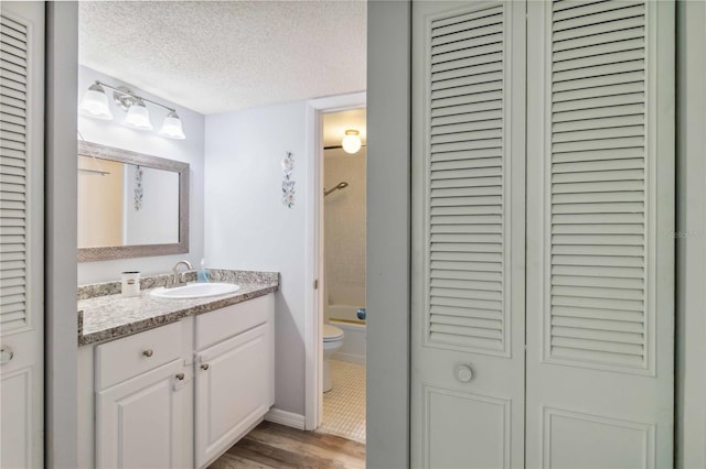 full bathroom with vanity, toilet, bathtub / shower combination, a textured ceiling, and a closet