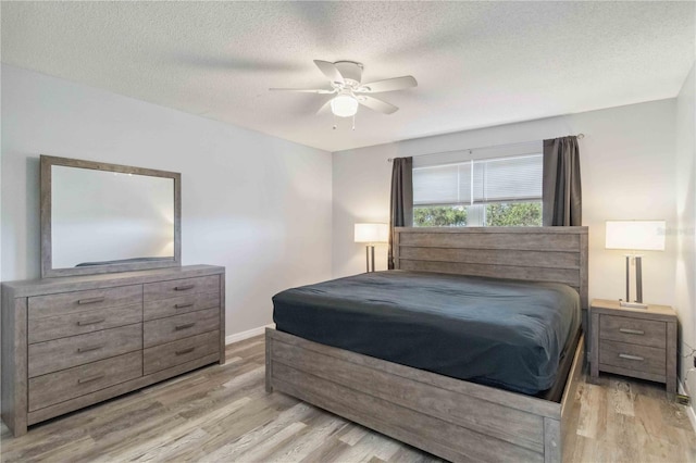 bedroom with a ceiling fan, a textured ceiling, baseboards, and wood finished floors