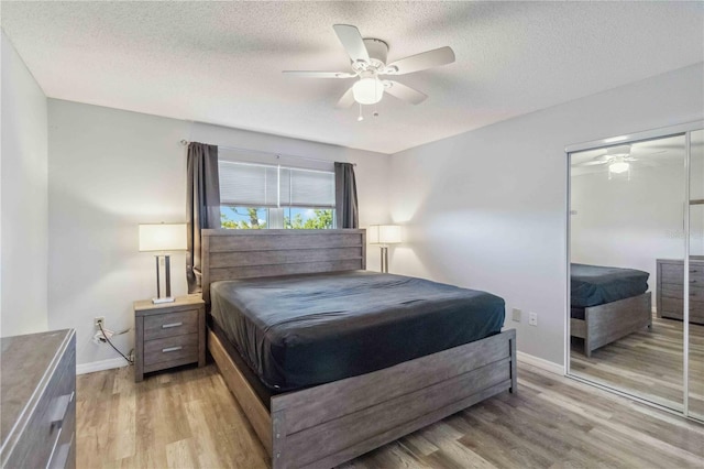bedroom featuring baseboards, a closet, light wood finished floors, and a textured ceiling