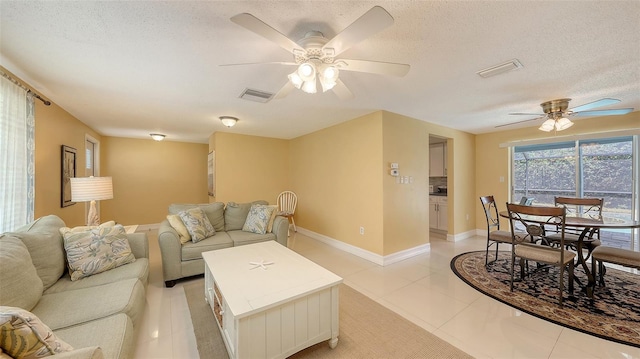 living room featuring a textured ceiling, ceiling fan, and visible vents