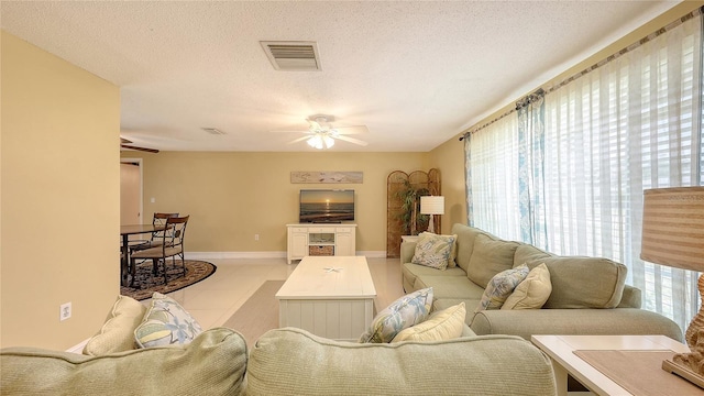tiled living area with baseboards, visible vents, a ceiling fan, and a textured ceiling
