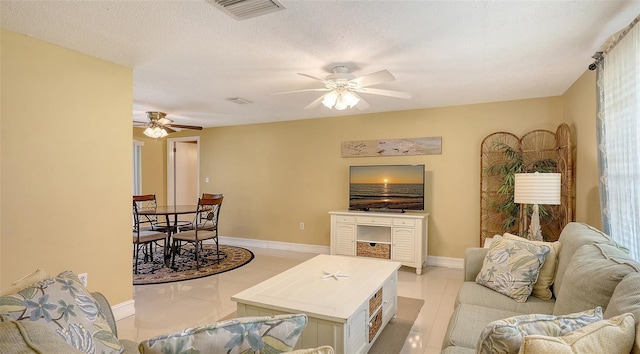 living room with baseboards, visible vents, light tile patterned floors, and a ceiling fan